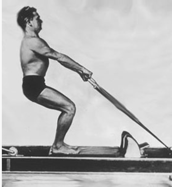 Archival photograph of Joseph Pilates on the Reformer
